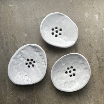 Three white glazed embossed ceramic soap dishes