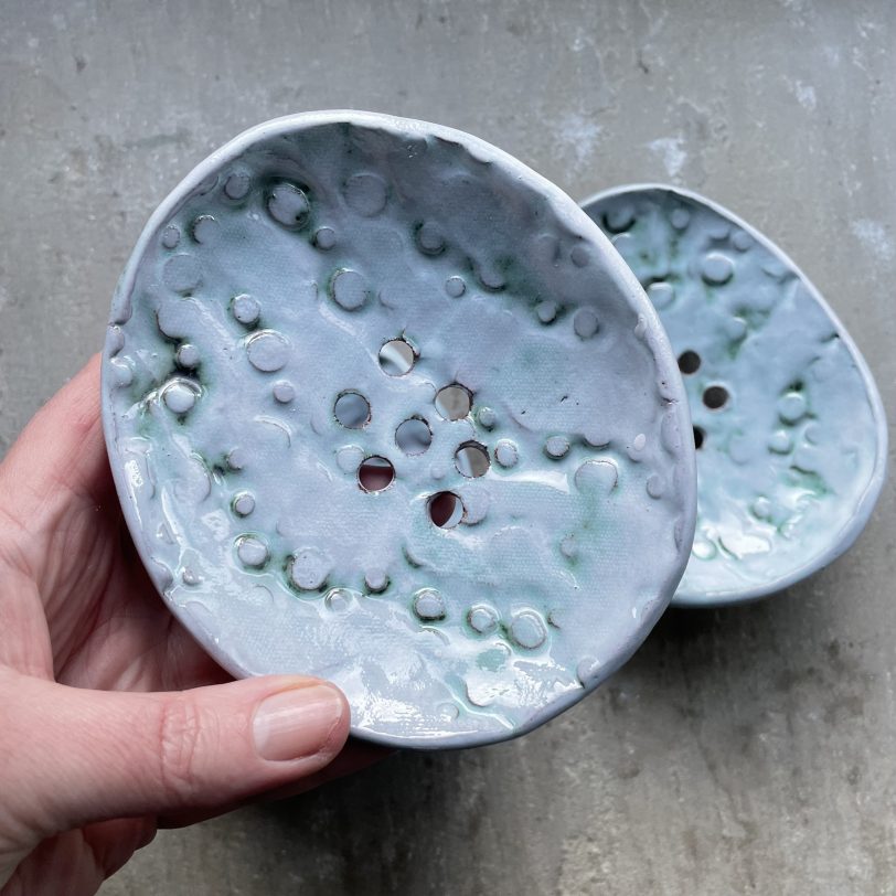 Hand holding iridescent ceramic soap dish